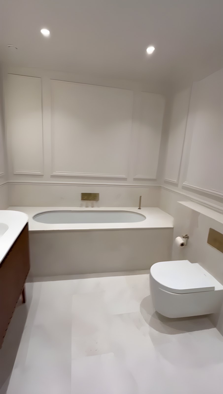 Bathroom with panelled walls, inset bath, brass fittings and wall-hung WC